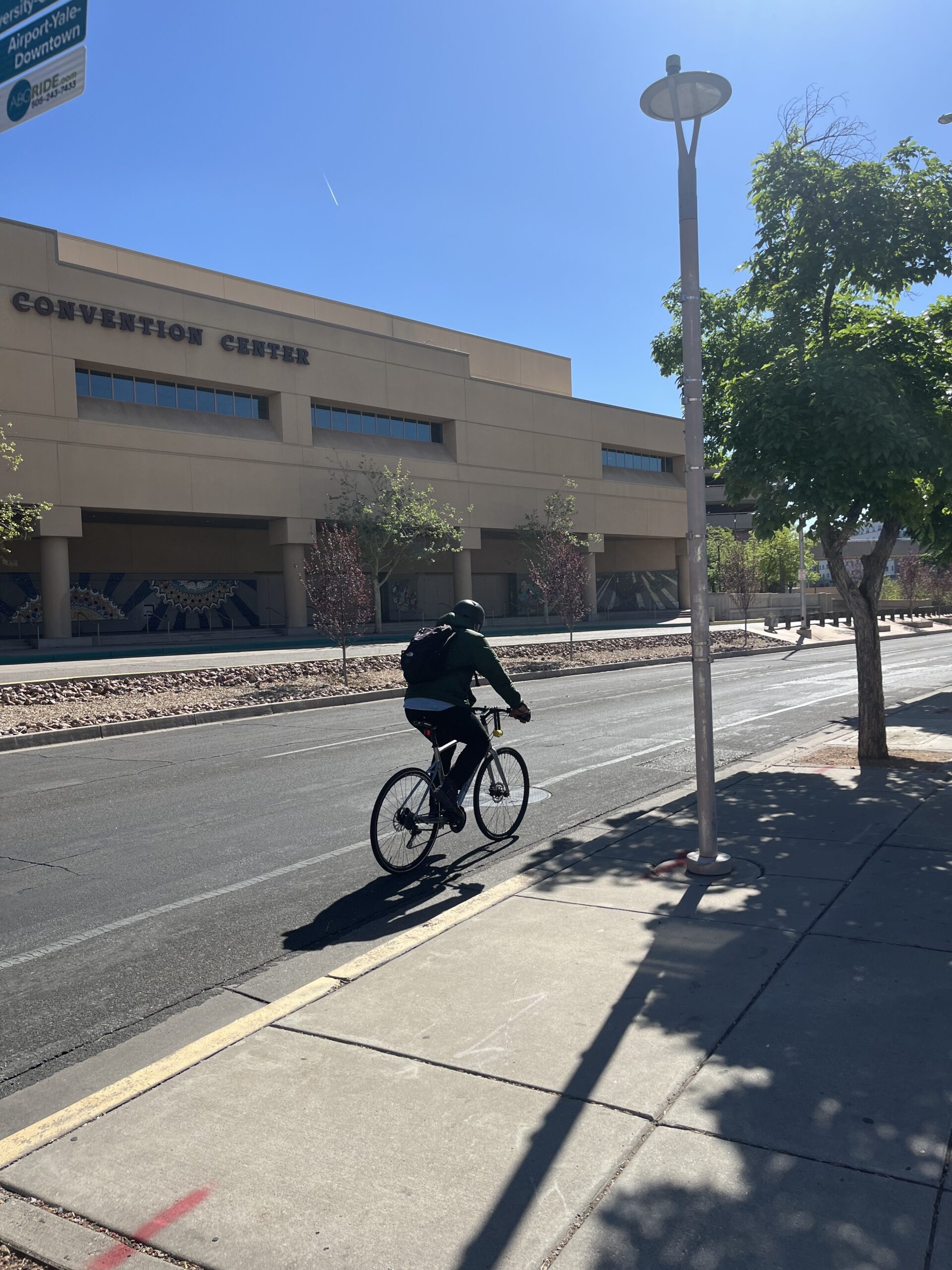 A bicyclist rides in the street under blue skies.