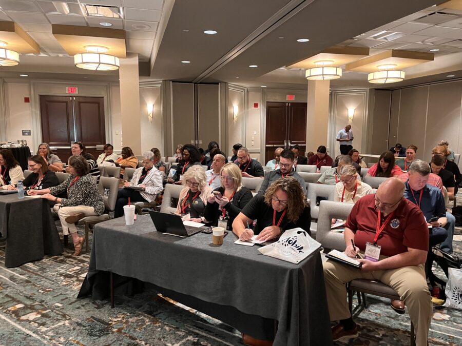 Many people sit in a conference room writing on notecards