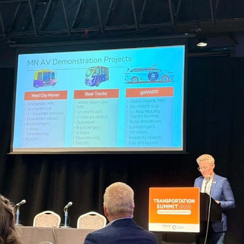 A person stands behind a podium giving a presentation with a slide deck.